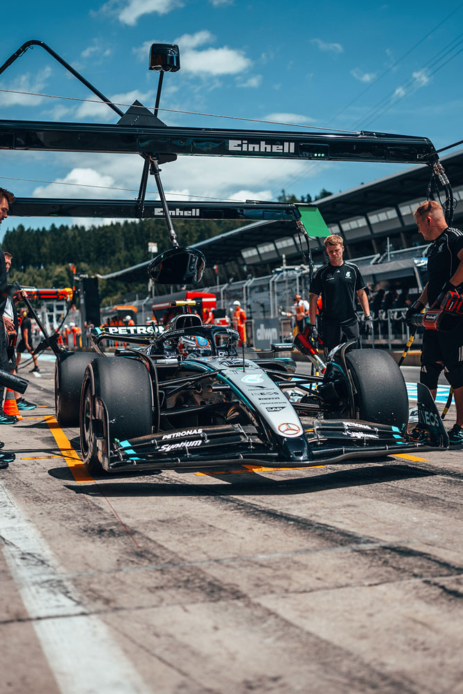 Una vettura Mercedes-AMG di Formula 1 si trova nella corsia dei box, circondata dai membri del team sotto la struttura del garage Einhell.