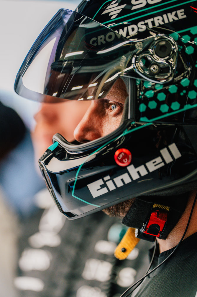 Un membro dell'equipaggio di Formula 1 indossa un casco e guarda di lato con attenzione.