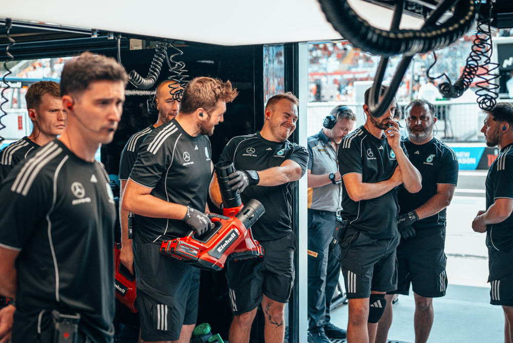 Il Mercedes-AMG PETRONAS Formula One Team si trova nel garage. Due membri del team tengono soffiatori senza fili rossi Einhell, preparandosi per la prossima azione.