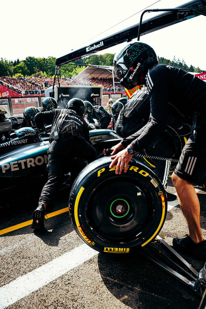 I meccanici del Mercedes-AMG PETRONAS Formula One Team stanno effettuando un pit stop. Un membro del team prepara una gomma Pirelli mentre altri lavorano sull’auto. Il marchio Einhell è visibile sull’attrezzatura sopra la vettura.