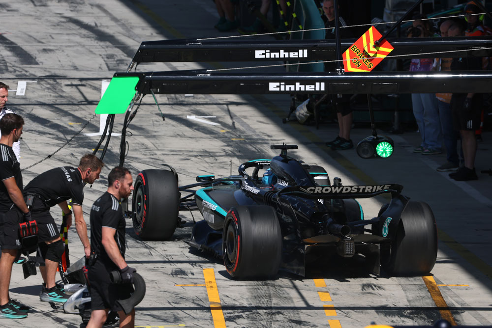 Un’auto del Mercedes-AMG PETRONAS Formula One Team si trova nella corsia dei box durante un pit stop. Diversi membri del team sono intorno all’auto. Il marchio Einhell è visibile sopra l’area dei box.