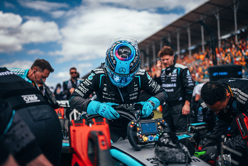 Pilota di Formula 1 seduto nella vettura circondato dal team sulla griglia di partenza.