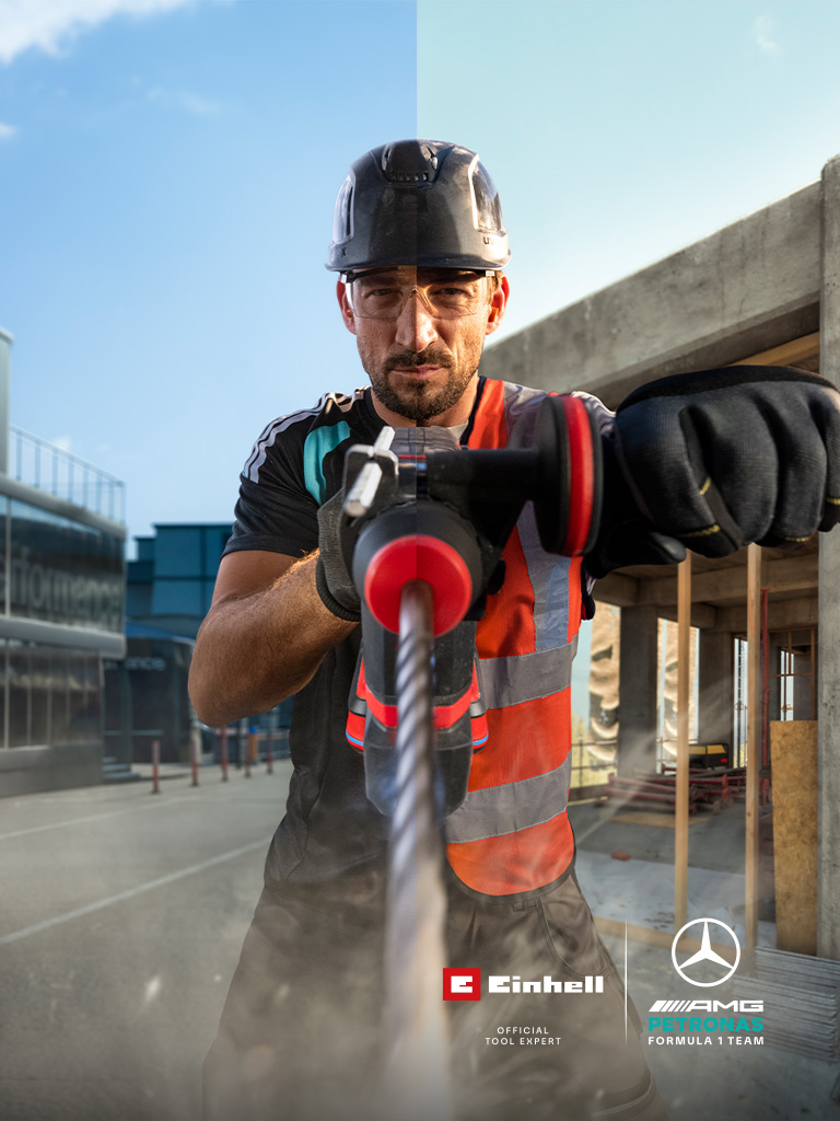 Un meccanico in tenuta protettiva che esegue una foratura con un utensile elettrico in un cantiere.